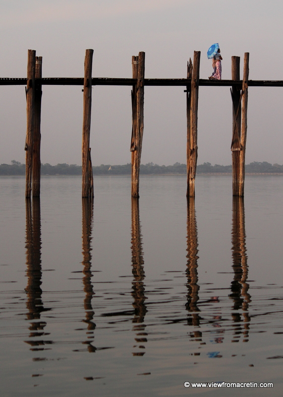 A couple strolls across U Bein's Bridge in Amarapura at sunset.